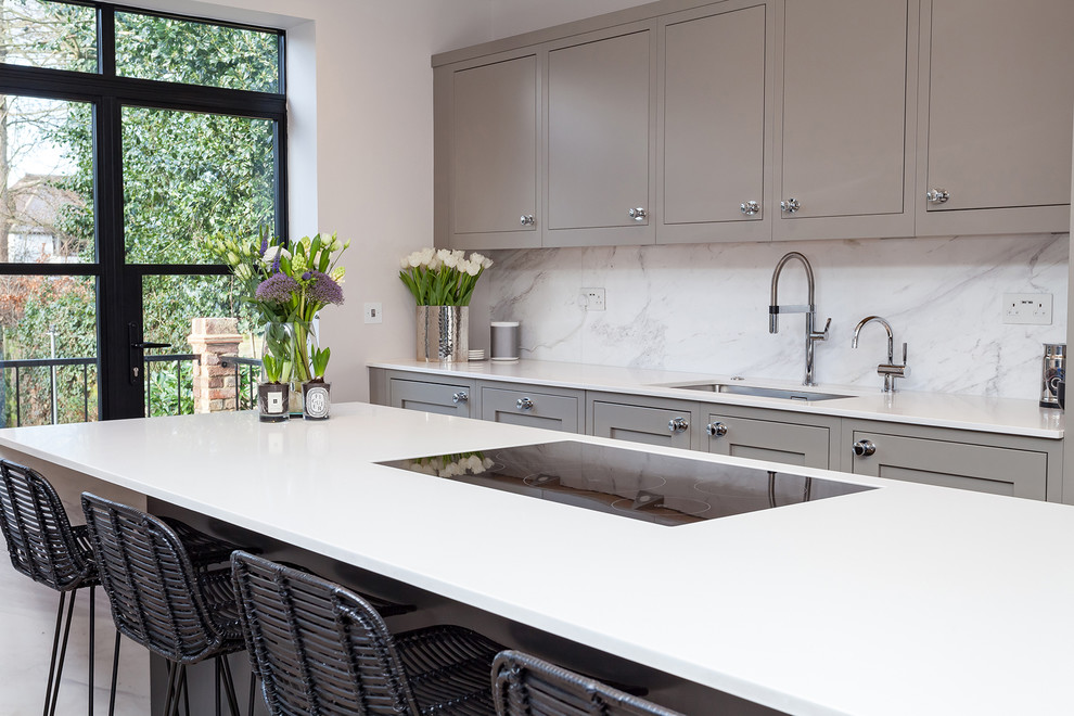 Photo of a mid-sized contemporary galley eat-in kitchen in London with an integrated sink, grey cabinets, quartzite benchtops, white splashback, marble splashback, panelled appliances, with island, flat-panel cabinets, grey floor and white benchtop.