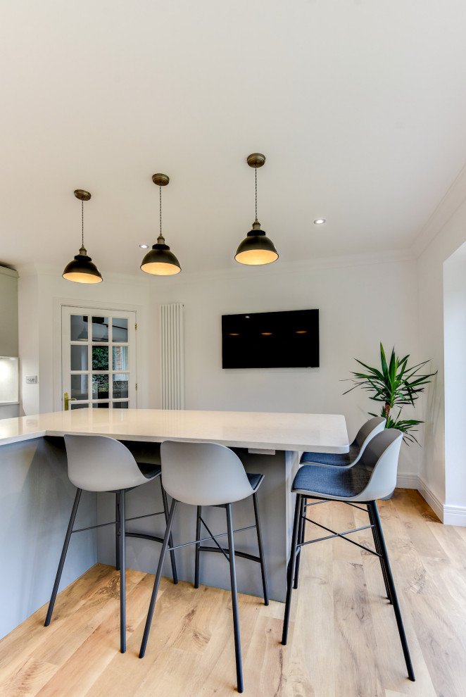 Inspiration for a large contemporary u-shaped open plan kitchen in Sussex with an undermount sink, shaker cabinets, grey cabinets, quartzite benchtops, white splashback, panelled appliances, medium hardwood floors, with island, brown floor and white benchtop.