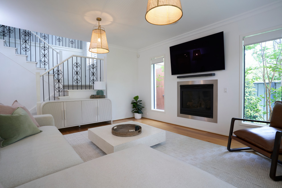 This is an example of a medium sized contemporary open plan living room in Melbourne with white walls, medium hardwood flooring, a ribbon fireplace, a plastered fireplace surround, a wall mounted tv and brown floors.
