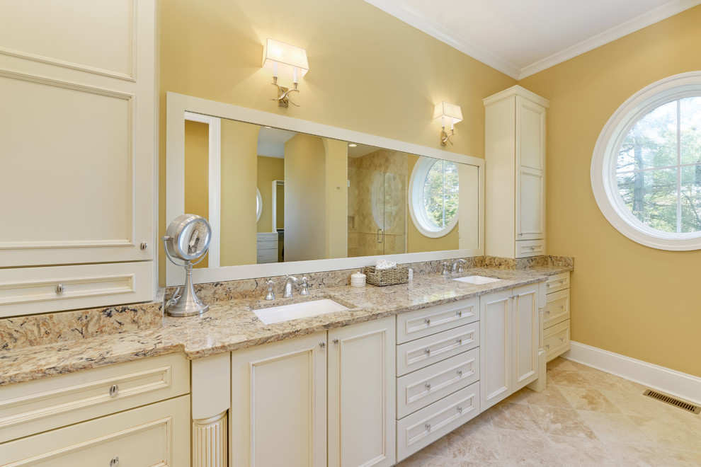 Mid-sized mountain style master beige tile and stone tile marble floor bathroom photo with recessed-panel cabinets, white cabinets, yellow walls and a drop-in sink