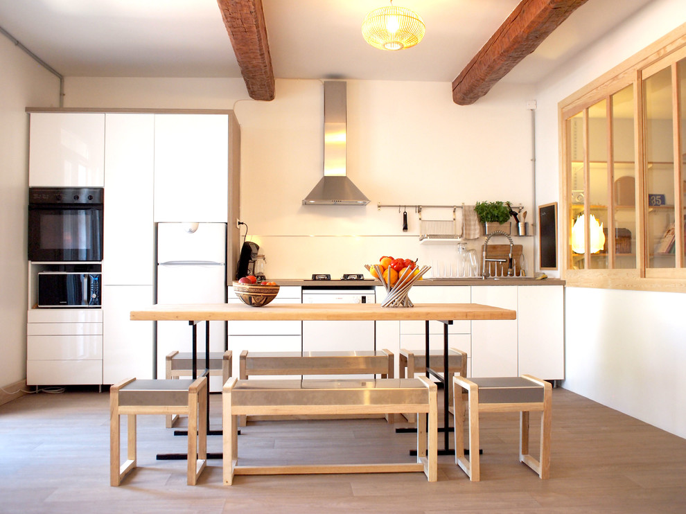 Mid-sized scandinavian single-wall eat-in kitchen in Toulouse with a drop-in sink, flat-panel cabinets, white cabinets, wood benchtops, white splashback, medium hardwood floors, no island, brown floor and brown benchtop.