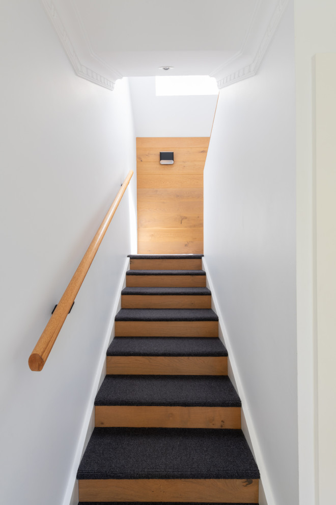 Diseño de escalera en U actual de tamaño medio con escalones enmoquetados, contrahuellas de madera, barandilla de madera y madera