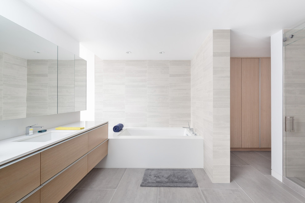 Photo of a large modern master bathroom in Los Angeles with an undermount sink, flat-panel cabinets, light wood cabinets, engineered quartz benchtops, an undermount tub, an alcove shower, gray tile, porcelain tile, white walls, porcelain floors and a two-piece toilet.