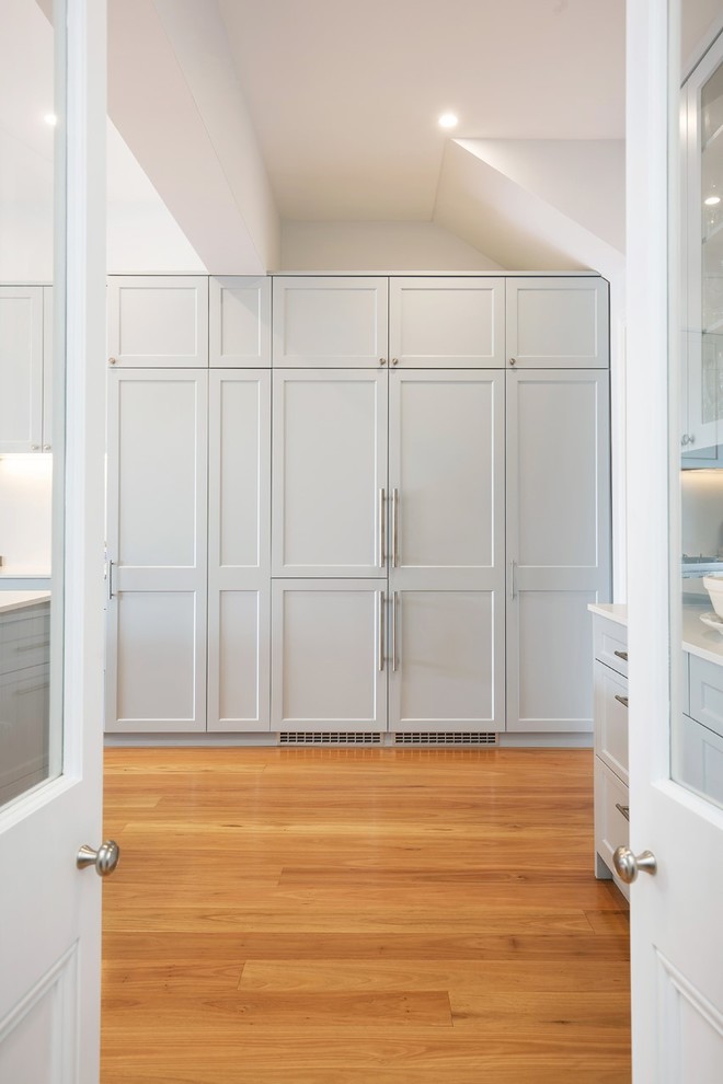 Inspiration for a mid-sized beach style single-wall kitchen pantry in Sydney with shaker cabinets, grey cabinets, medium hardwood floors, with island and brown floor.