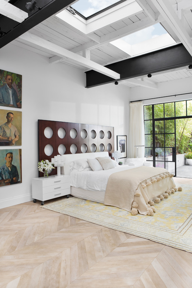 Large eclectic master bedroom in Other with white walls, light hardwood floors, a ribbon fireplace and brown floor.