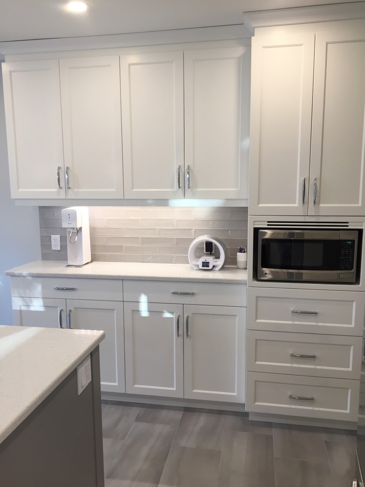 Large transitional u-shaped eat-in kitchen in Ottawa with an undermount sink, shaker cabinets, white cabinets, grey splashback, subway tile splashback, stainless steel appliances, ceramic floors, with island and quartzite benchtops.