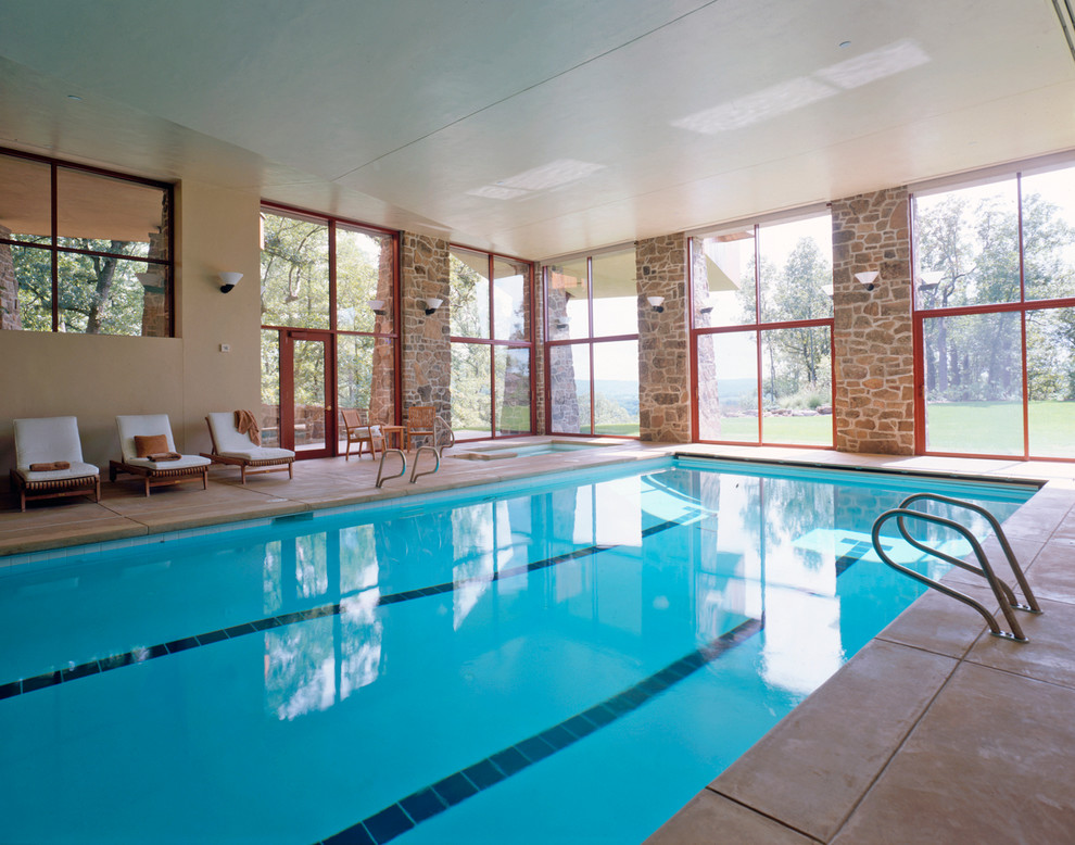This is an example of a large contemporary indoor rectangular pool in St Louis with a hot tub and concrete slab.