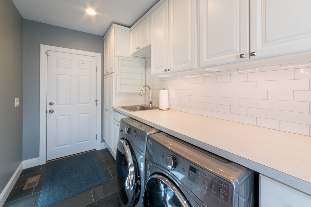 This is an example of a mid-sized transitional single-wall dedicated laundry room in DC Metro with an undermount sink, raised-panel cabinets, white cabinets, laminate benchtops, ceramic floors, a side-by-side washer and dryer, black floor and grey walls.