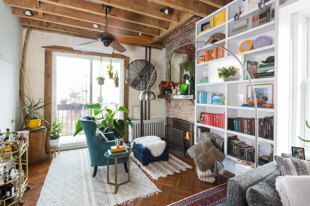Inspiration for an eclectic living room in New York with white walls, medium hardwood floors, a standard fireplace, a brick fireplace surround and brown floor.