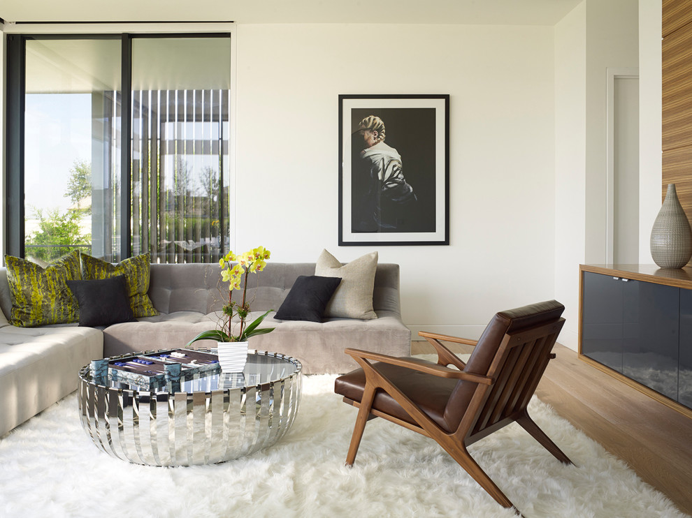 This is an example of a contemporary family room in New York with white walls and light hardwood floors.