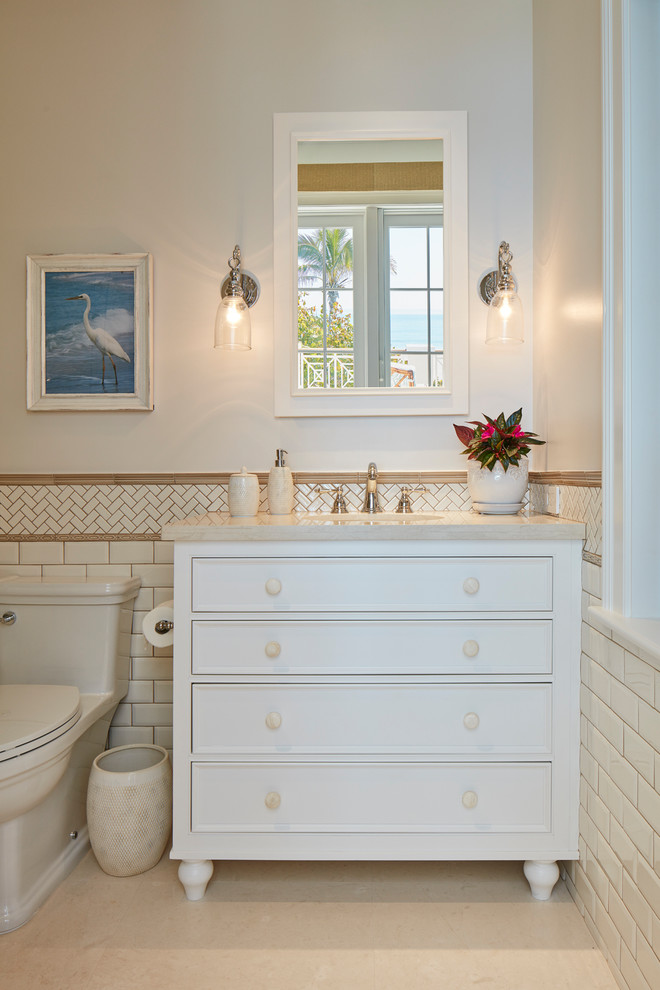 Inspiration for a small beach style 3/4 bathroom in Denver with furniture-like cabinets, white cabinets, a one-piece toilet, beige tile, white tile, porcelain tile, white walls, porcelain floors, an undermount sink, soapstone benchtops and beige floor.