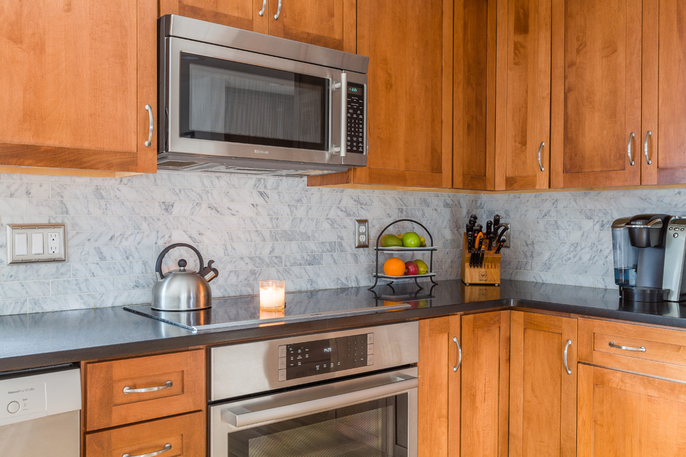 Mid-sized transitional u-shaped medium tone wood floor eat-in kitchen photo in Boston with a farmhouse sink, beaded inset cabinets, medium tone wood cabinets, marble countertops, gray backsplash, marble backsplash, stainless steel appliances, a peninsula and gray countertops