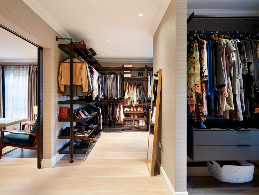 Design ideas for a large contemporary gender-neutral walk-in wardrobe in Surrey with open cabinets, black cabinets and light hardwood floors.