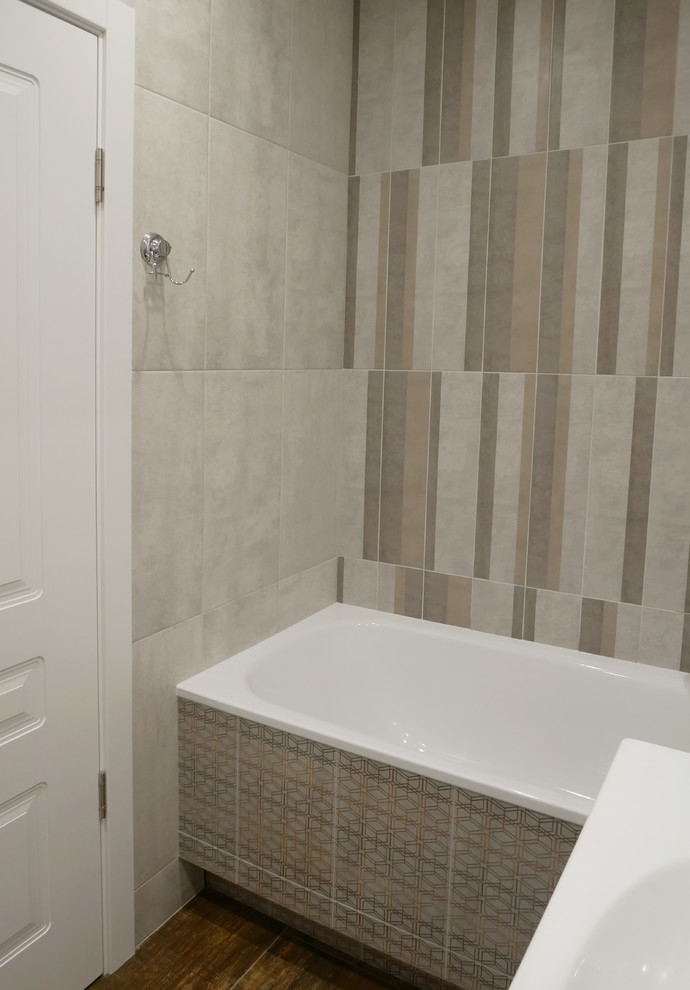 Photo of a small scandinavian master bathroom in Moscow with flat-panel cabinets, white cabinets, a claw-foot tub, a shower/bathtub combo, a wall-mount toilet, gray tile, porcelain tile, grey walls, porcelain floors, a drop-in sink, solid surface benchtops, brown floor, an open shower and white benchtops.