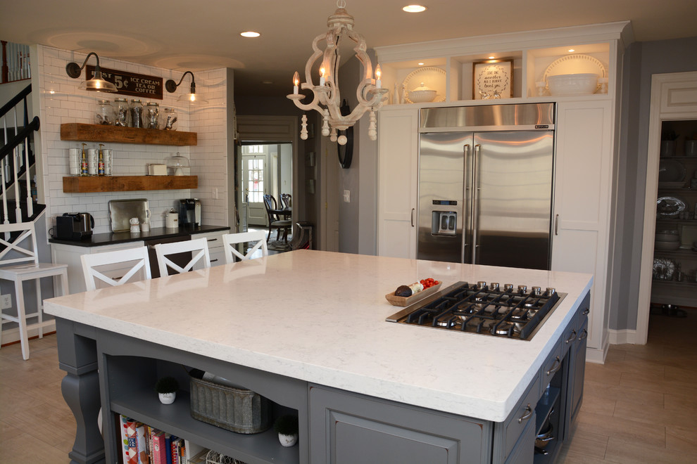 Example of a large transitional u-shaped eat-in kitchen design in DC Metro with a farmhouse sink, white cabinets, quartz countertops, white backsplash, ceramic backsplash, stainless steel appliances and an island