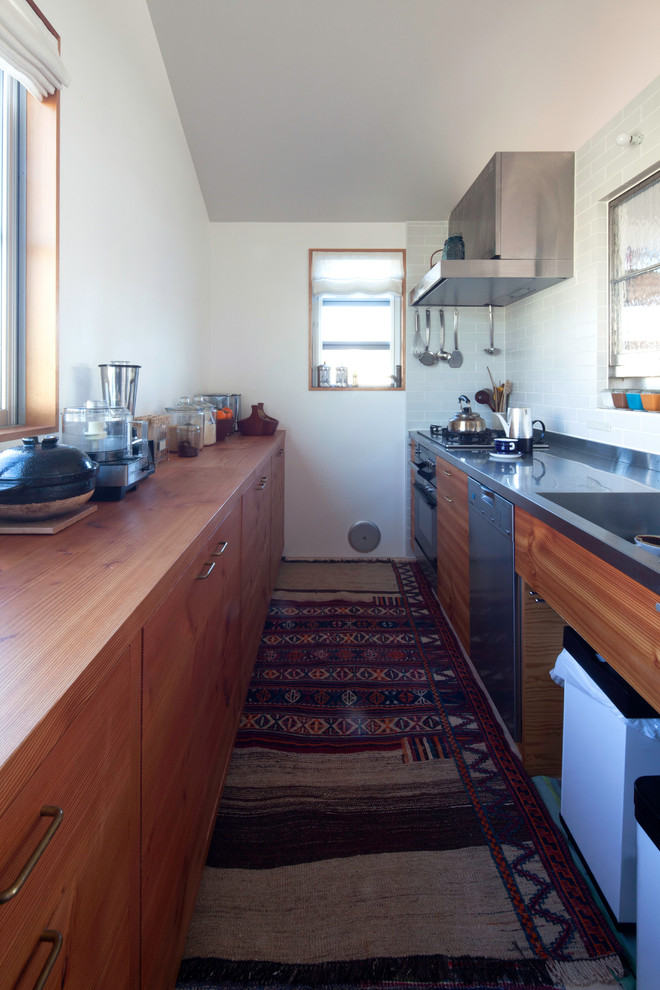 Mid-sized scandinavian galley separate kitchen in Tokyo with an integrated sink, shaker cabinets, medium wood cabinets, stainless steel benchtops, white splashback, ceramic splashback, stainless steel appliances, carpet and multi-coloured floor.