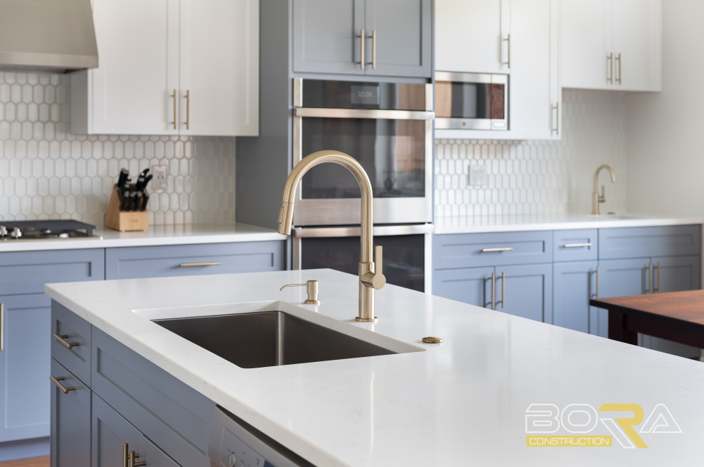 Eat-in kitchen - large transitional l-shaped medium tone wood floor and brown floor eat-in kitchen idea in Seattle with an undermount sink, shaker cabinets, blue cabinets, quartz countertops, white backsplash, ceramic backsplash, stainless steel appliances, an island and white countertops