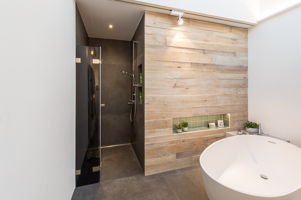 Mid-sized contemporary 3/4 bathroom in Other with a freestanding tub, a curbless shower, green tile, ceramic tile, beige walls, cement tiles, black floor and a hinged shower door.