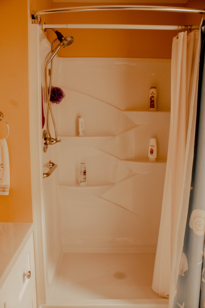 Alcove shower - small transitional 3/4 vinyl floor, brown floor and single-sink alcove shower idea with shaker cabinets, white cabinets, a two-piece toilet, beige walls, an undermount sink, marble countertops, white countertops and a freestanding vanity