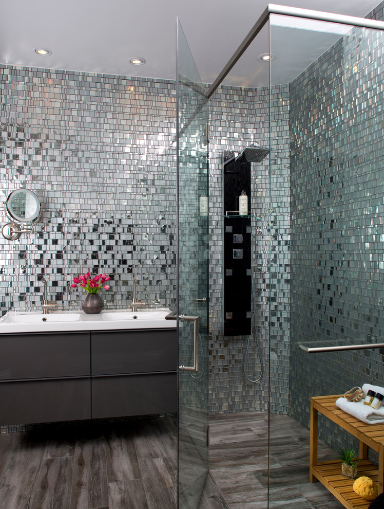 Inspiration for a mid-sized modern bathroom in Tampa with flat-panel cabinets, grey cabinets, a curbless shower, mirror tile, grey walls, porcelain floors, a drop-in sink, grey floor and a hinged shower door.