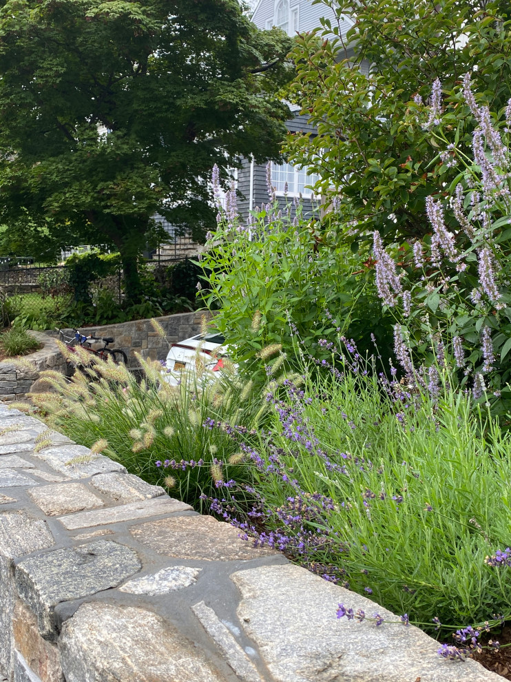 Inspiration for a large eclectic front yard driveway in New York with a retaining wall and natural stone pavers.