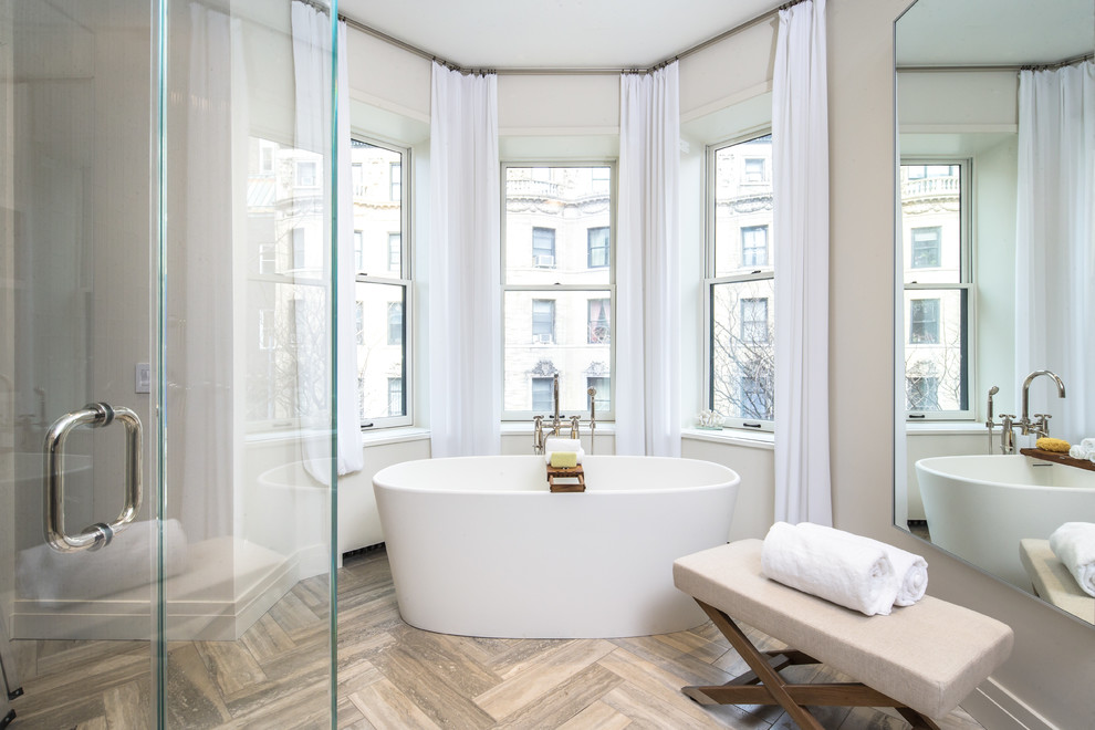 Photo of an expansive contemporary master bathroom in New York with a freestanding tub, stone tile and travertine floors.
