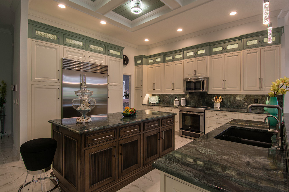 This is an example of a large tropical u-shaped eat-in kitchen in Tampa with an undermount sink, beaded inset cabinets, white cabinets, quartzite benchtops, green splashback, stone slab splashback, stainless steel appliances and porcelain floors.