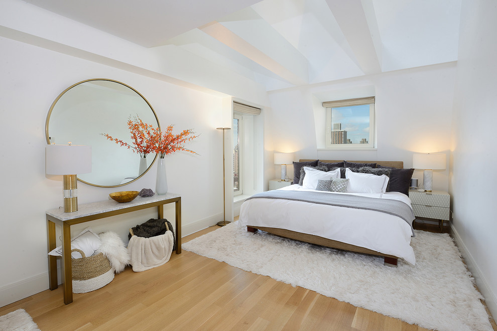 Design ideas for a contemporary bedroom in New York with white walls, medium hardwood floors and brown floor.