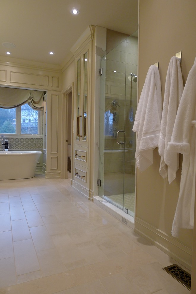 This is an example of a transitional bathroom in Indianapolis with furniture-like cabinets, beige cabinets, a freestanding tub, an alcove shower, a one-piece toilet, beige tile and porcelain tile.