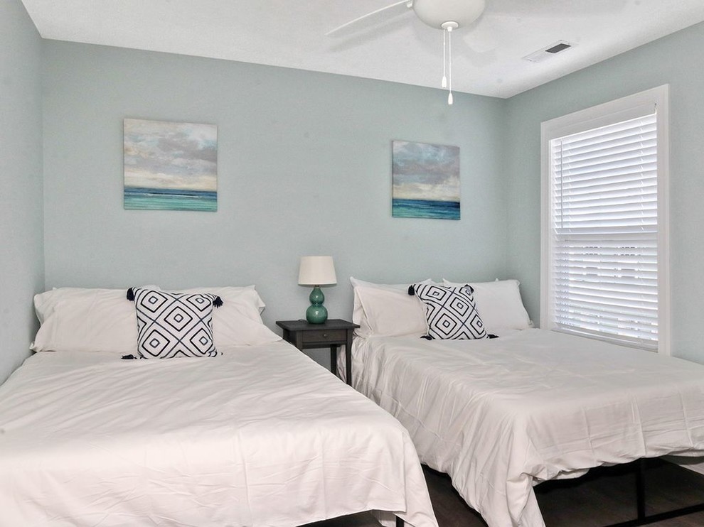This is an example of a mid-sized beach style guest bedroom in Other with blue walls, medium hardwood floors and brown floor.