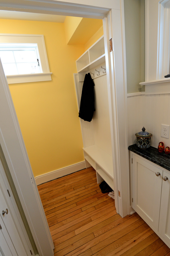 Design ideas for a small traditional mudroom in Cleveland with yellow walls and light hardwood floors.