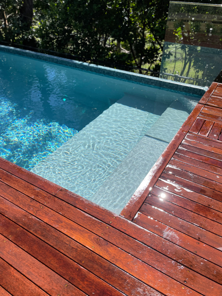 Foto de piscina minimalista rectangular en patio delantero con paisajismo de piscina y entablado