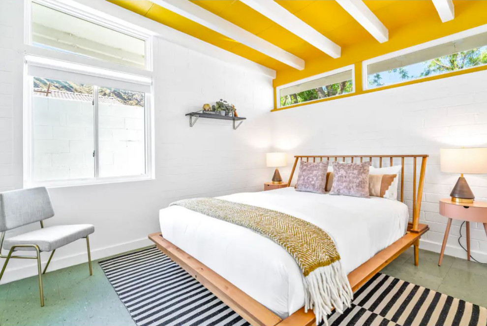 Foto di una camera degli ospiti minimalista con pareti bianche, pavimento in laminato, pavimento verde, travi a vista e pareti in mattoni
