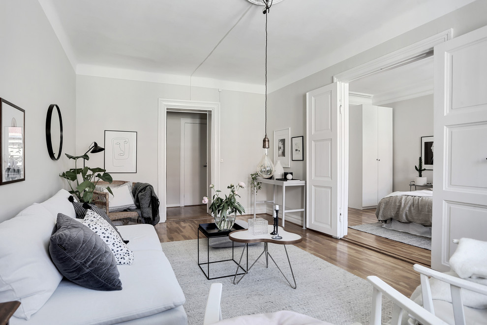 Inspiration for a mid-sized traditional living room in Gothenburg with white walls, medium hardwood floors and multi-coloured floor.