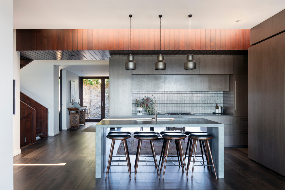 This is an example of a contemporary galley kitchen in Sydney with a double-bowl sink, flat-panel cabinets, grey cabinets, grey splashback, dark hardwood floors, with island and brown floor.