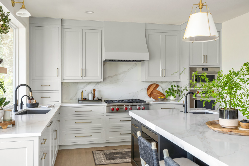 Inspiration for a mid-sized transitional l-shaped light wood floor and brown floor open concept kitchen remodel in Seattle with an undermount sink, shaker cabinets, white cabinets, quartz countertops, white backsplash, quartz backsplash, stainless steel appliances, an island and white countertops