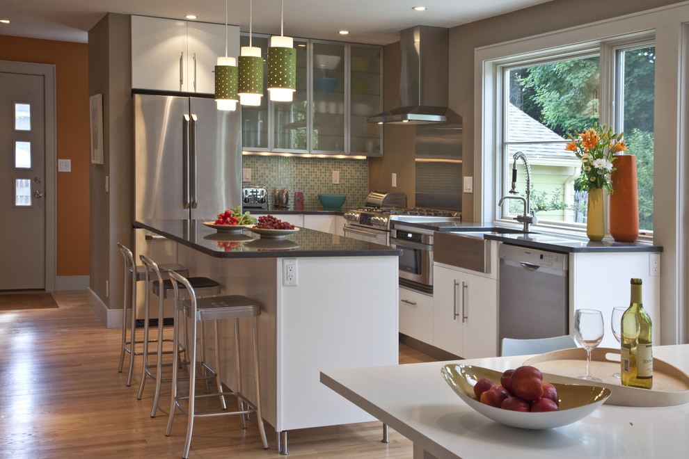 This is an example of a contemporary kitchen in Boston with glass-front cabinets, white cabinets, metallic splashback, metal splashback and stainless steel appliances.