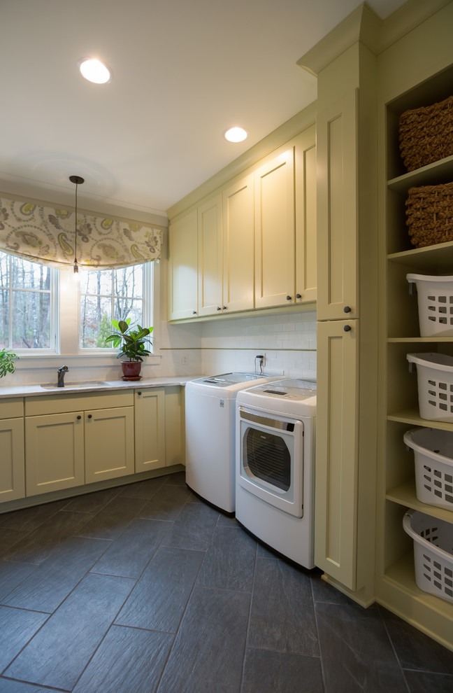 Design ideas for a country u-shaped laundry room in Charlotte with an undermount sink, shaker cabinets, yellow cabinets, beige walls and slate floors.
