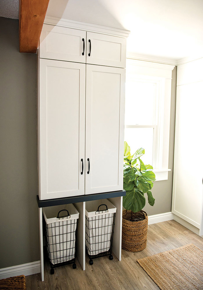 This is an example of a small country u-shaped utility room in Other with shaker cabinets, white cabinets, wood benchtops, white walls, vinyl floors, a side-by-side washer and dryer, grey floor and brown benchtop.