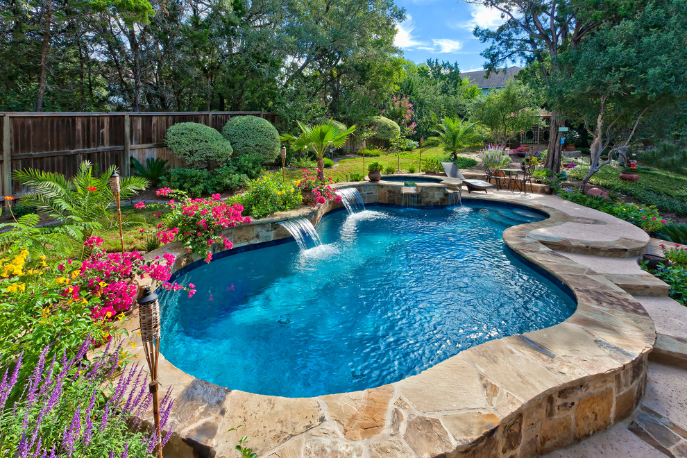Design ideas for a mid-sized traditional backyard custom-shaped natural pool in Austin with a hot tub and natural stone pavers.