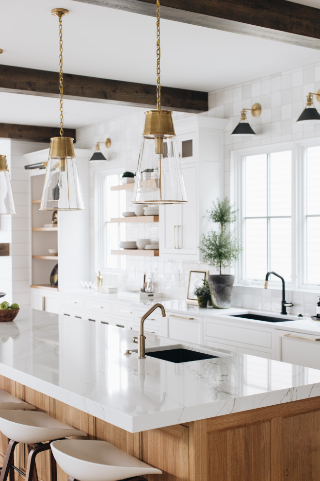 Example of a large beach style l-shaped light wood floor and exposed beam kitchen design in Grand Rapids with white cabinets, quartzite countertops, white backsplash, ceramic backsplash, stainless steel appliances, an island and white countertops