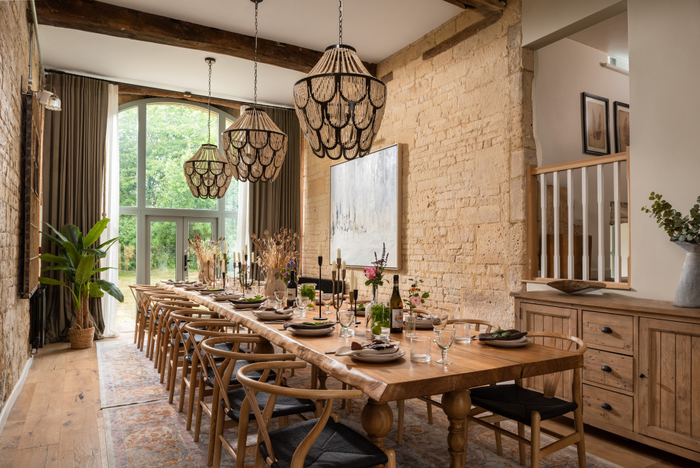 This is an example of a large country open plan dining in Gloucestershire with beige walls, medium hardwood floors, beige floor and brick walls.