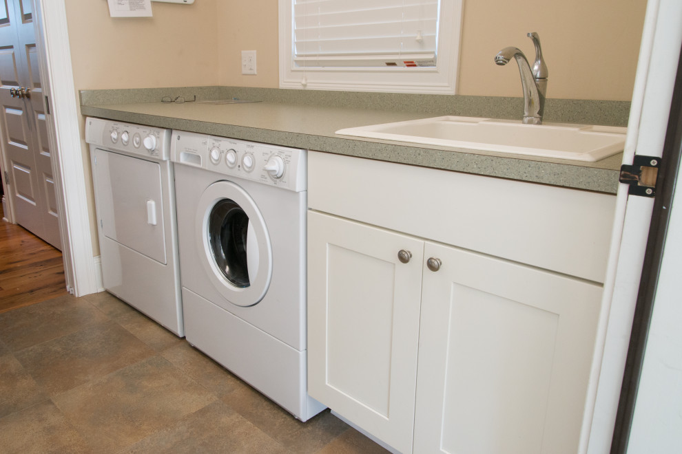 Photo of a mid-sized beach style single-wall utility room in Chicago with a drop-in sink, shaker cabinets, white cabinets, laminate benchtops, beige walls, ceramic floors, a side-by-side washer and dryer, beige floor and green benchtop.