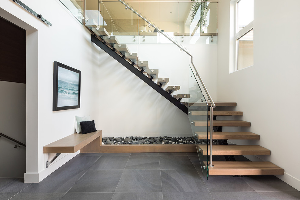 This is an example of a large contemporary foyer in Vancouver with white walls, ceramic floors, a pivot front door, a black front door and grey floor.