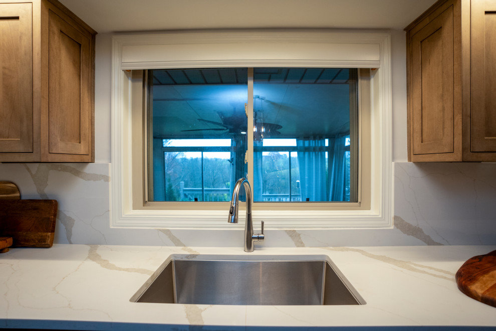 Eat-in kitchen - large transitional l-shaped medium tone wood floor and brown floor eat-in kitchen idea with a single-bowl sink, shaker cabinets, medium tone wood cabinets, quartz countertops, white backsplash, quartz backsplash, stainless steel appliances, an island and white countertops