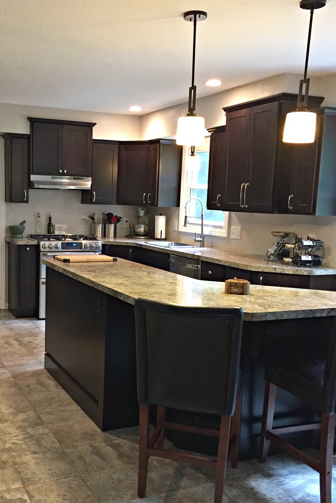 This is an example of a mid-sized transitional l-shaped open plan kitchen in Other with a drop-in sink, shaker cabinets, dark wood cabinets, granite benchtops, stainless steel appliances, limestone floors and with island.
