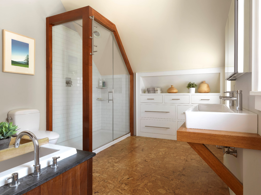 Design ideas for a country bathroom in Burlington with flat-panel cabinets, white cabinets, a drop-in tub, a corner shower, a one-piece toilet, white tile, subway tile, beige walls, cork floors, wood benchtops, brown floor, a hinged shower door and a trough sink.