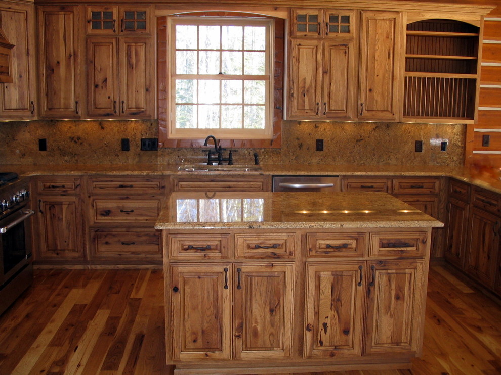 This is an example of a mid-sized country u-shaped eat-in kitchen in Minneapolis with flat-panel cabinets, medium wood cabinets, stainless steel appliances and medium hardwood floors.