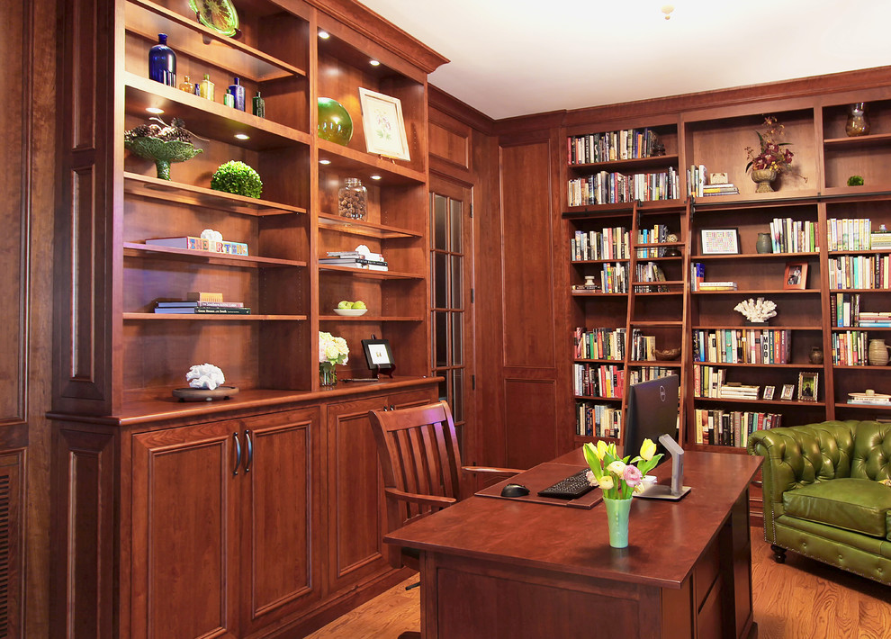 This is an example of a mid-sized traditional home office in Charlotte with a library, medium hardwood floors and a freestanding desk.