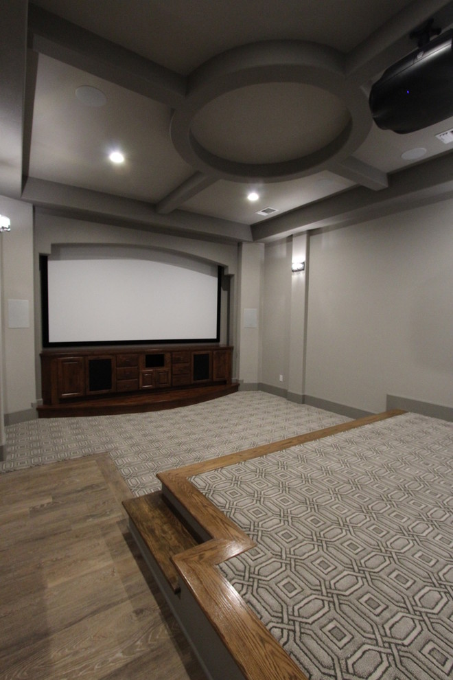 Photo of a large mediterranean enclosed home theatre in Austin with grey walls, carpet, a projector screen and grey floor.